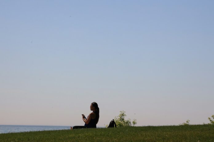 a woman sitting on top of a lush green hillside