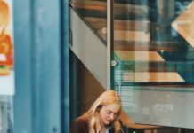 바쁜 일상 속 ‘마음 챙김 식사’ 실천법… 건강한 습관으로 거듭나기 Woman eating a sandwich at a cafe table.